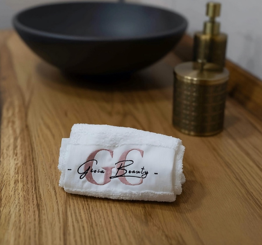 Gioia Beauty salon towels beside a black basin and brass containers